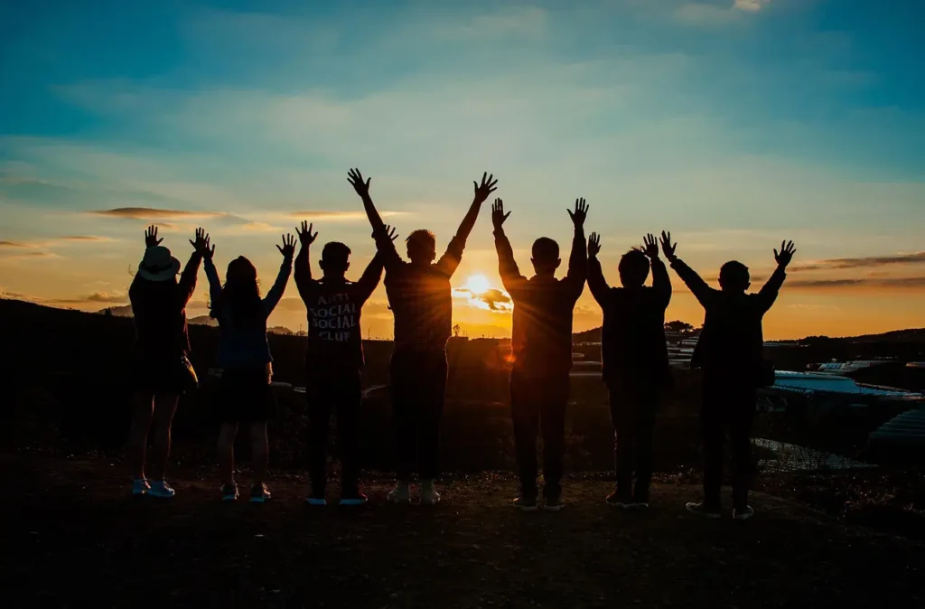 people standing with arms up at sunset-Parents Standing Together