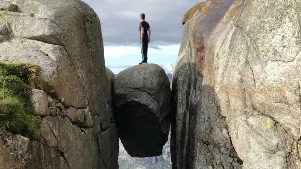 Teenager standing on bolder between 2 cliffs-Parents Standing Together